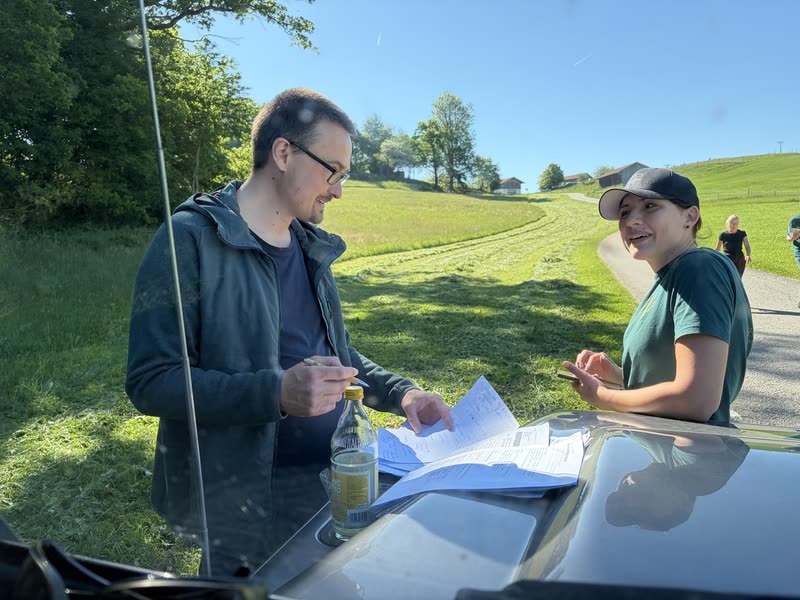 Landwirt und Helferin besprechen am Auto die Unterlagen zur Mahd